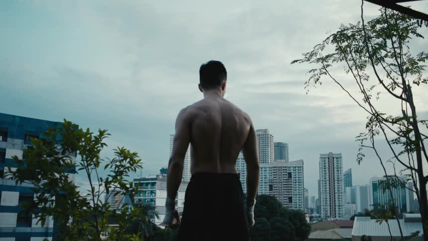 A man is standing before a city on a windy day