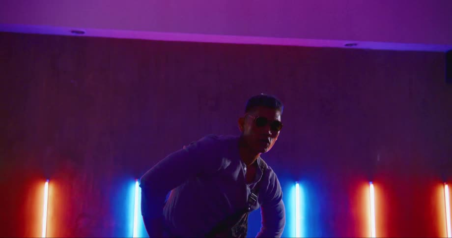 A man is dancing in an empty room surrounded with lights
