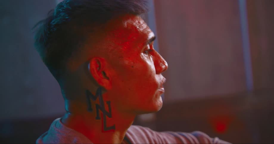 Asian man with a tattoo on his neck singing inside a room