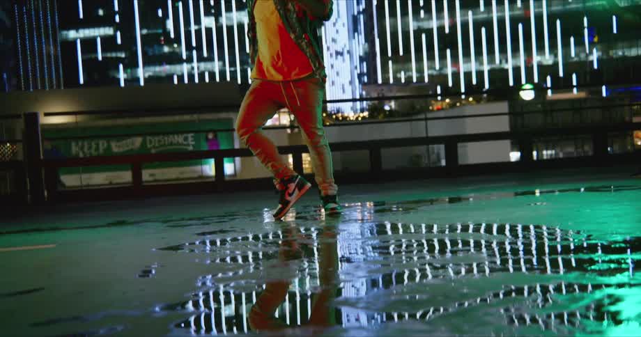 A man is dancing outdoors in a downtown city at night