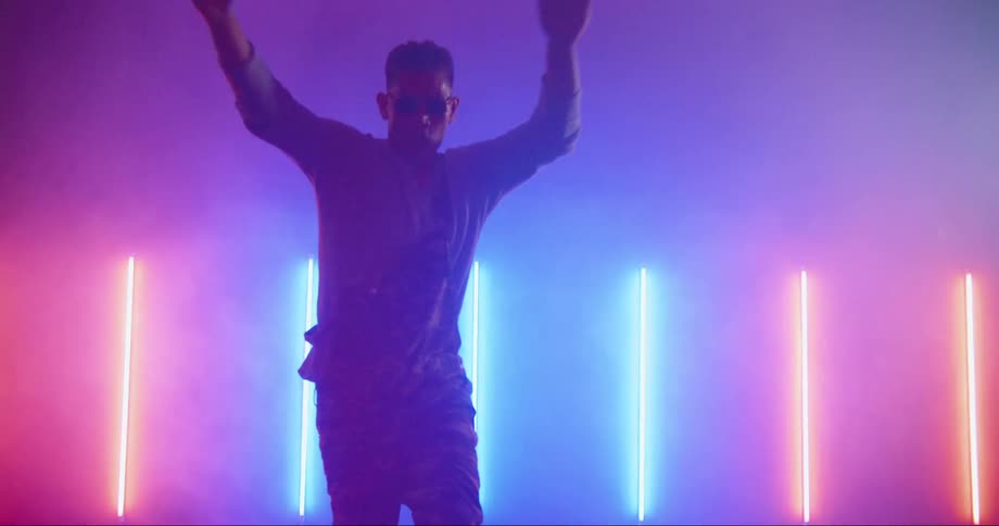 Young asian man dancing inside a room surrounded with colorful neon lights