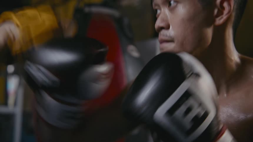 A man is boxing against someone indoors