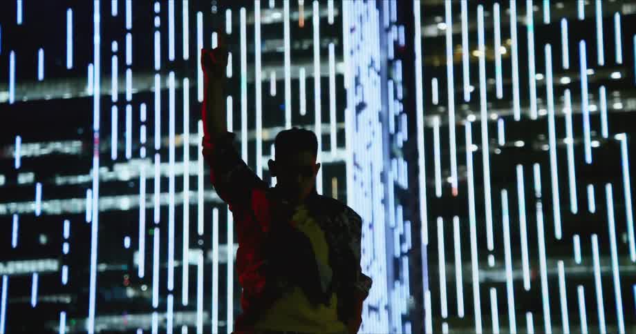 A man dances outside a lit up building in a city