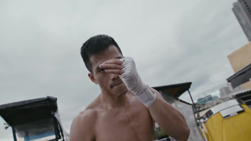 A man shadowboxing with motorcycles buildings the sky and clouds in the background