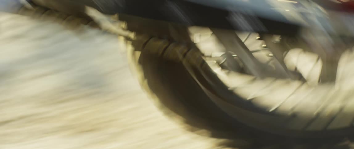 Person rides motorcycle quickly past woods