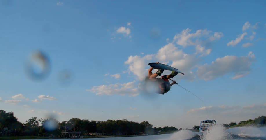A man does a flip while skurfing behind the boat