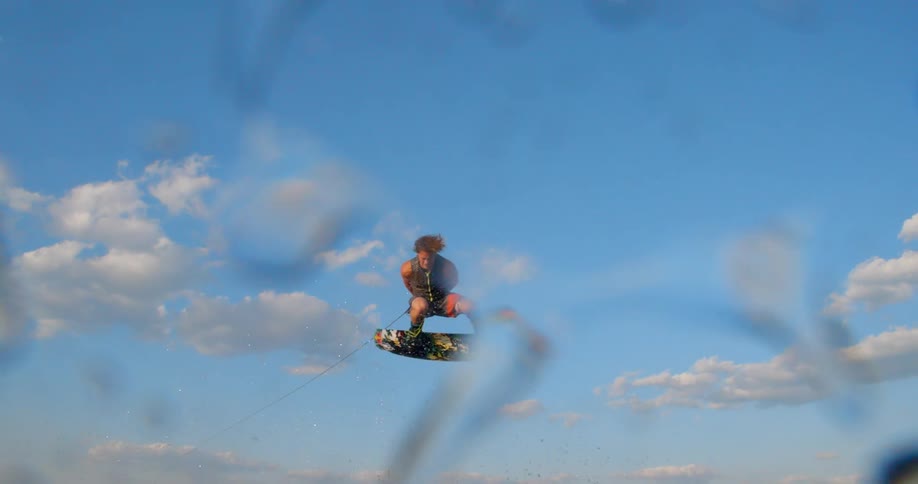 A man in a lake wake boarding with the sky and clouds in the background
