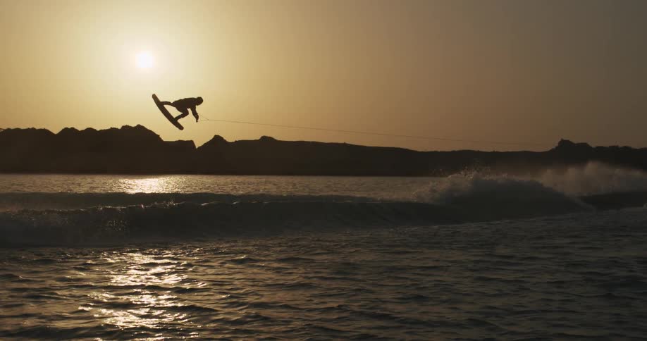 A person wakeboarding on the ocean waves with the sky and clouds in the background