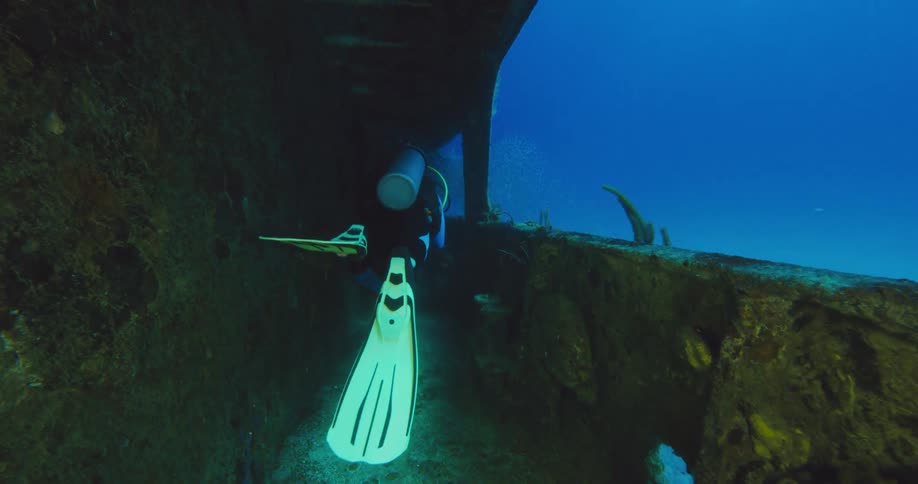 Scuba diver swimming insde the wreckage of a sunken ship in the ocean