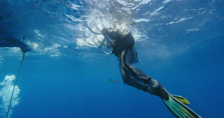 Scuba diver wearing an anti shark armored suit boarding a boat