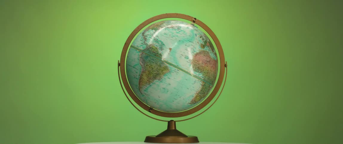 A world globe of earth is on a base spinning with colors changing in the background