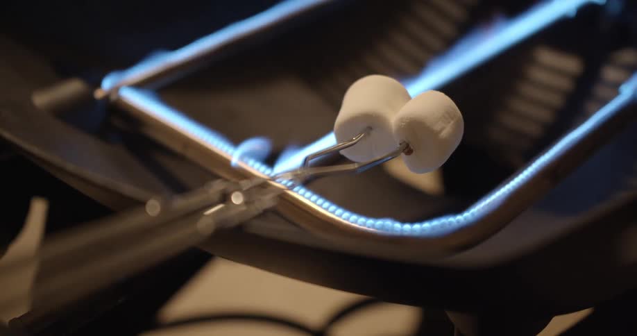 Two marshmallows cooking over a gas fire on the kitchen