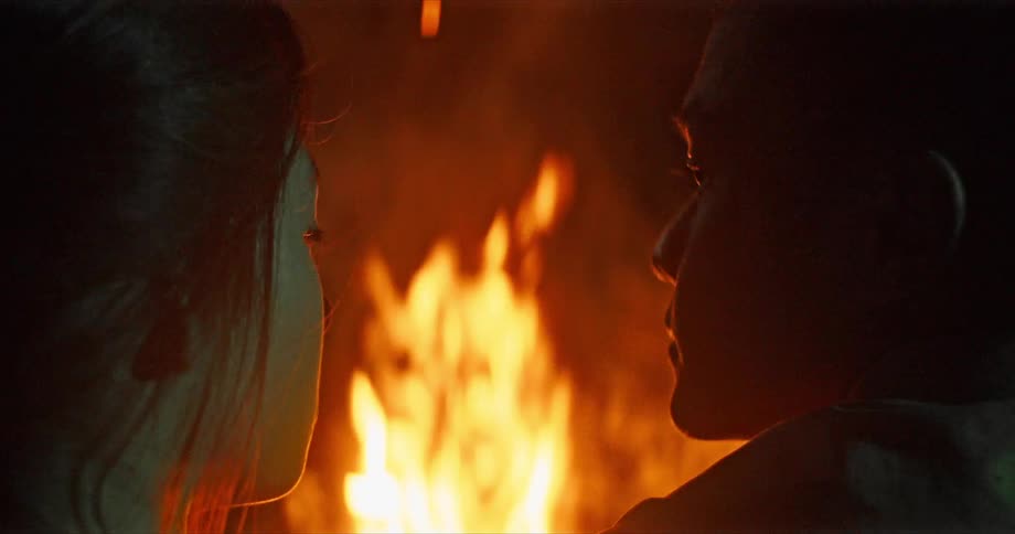A couple sit by the campfire together