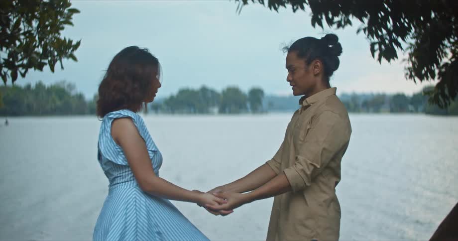 Young happy couple holding hands in front of a lake