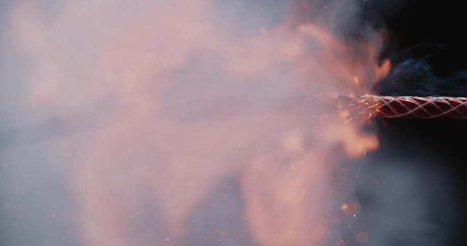 A lit wick sparks as it burns in flames and smoke