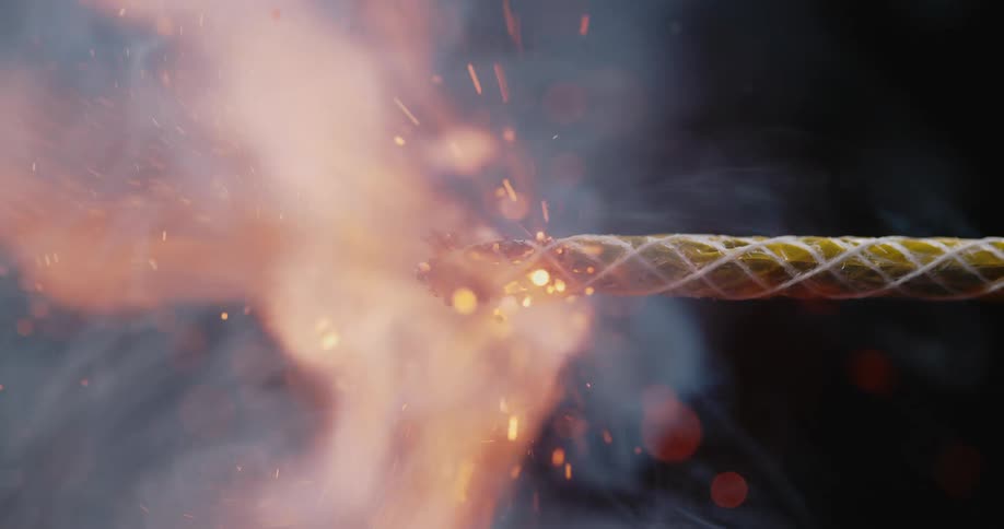 Shower of sparks and smoke as a match lights a fuse against a black background