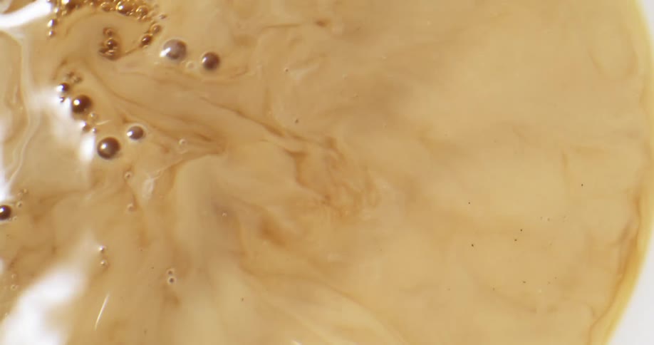 Milk or cream pouring on a cup of black coffee