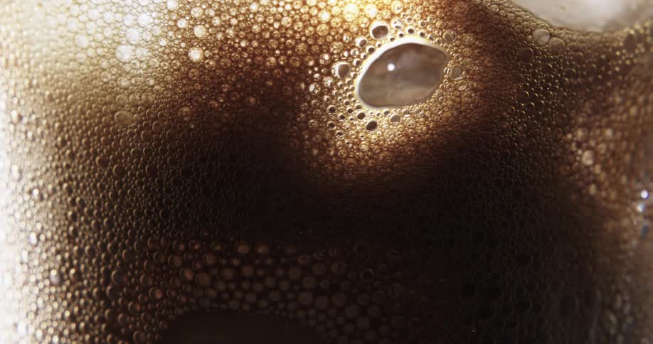 A frothy and bubbly layer of liquid persists within a transparent container