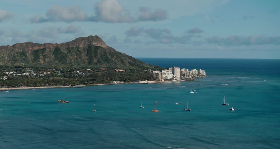 Boats floating in the ocean in front of a coastal city near a mountain