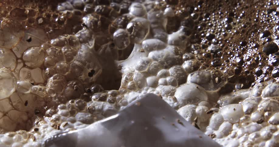 Chocolate being sprinkled on top of a beverage with bubbles