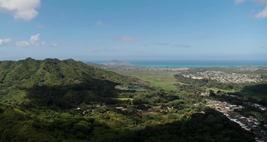 An aerial view of a landscape with hills and a neighborhood in front of water