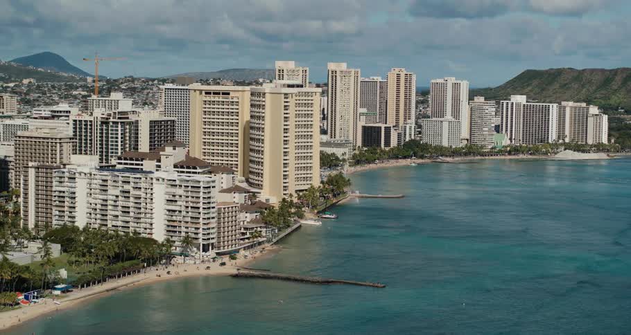 A city filled with skyscrapers is positioned at the edge of an inviting coastline