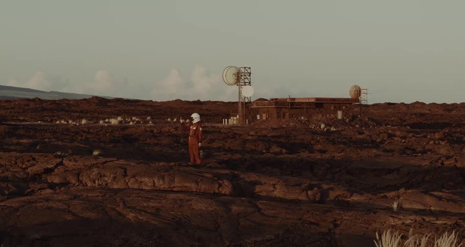 A person in a helmet stands in front of a utility plant and takes pictures