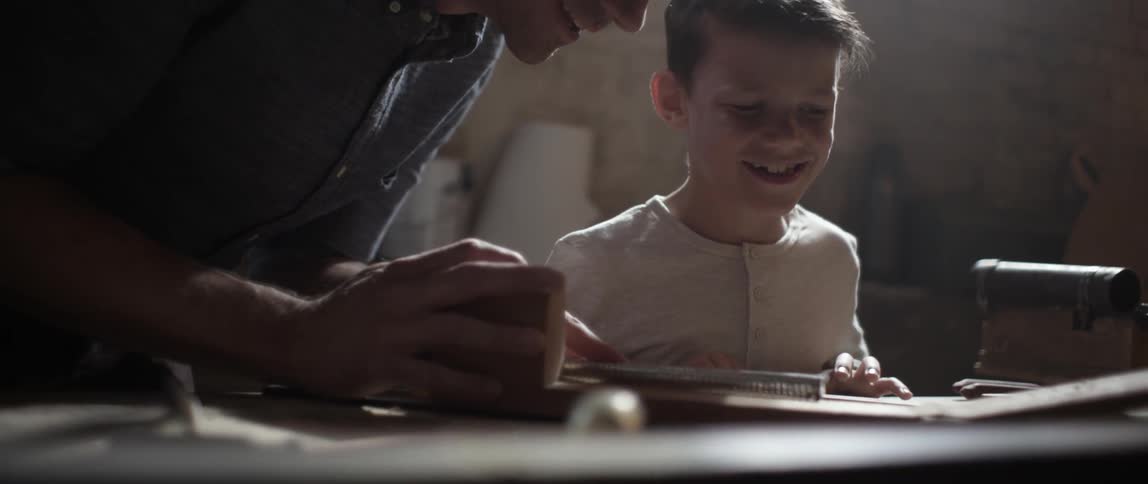 A man teaching a boy how to use a tool