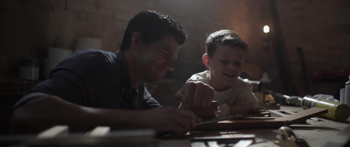 Man showing a young boy some crafting with his tools
