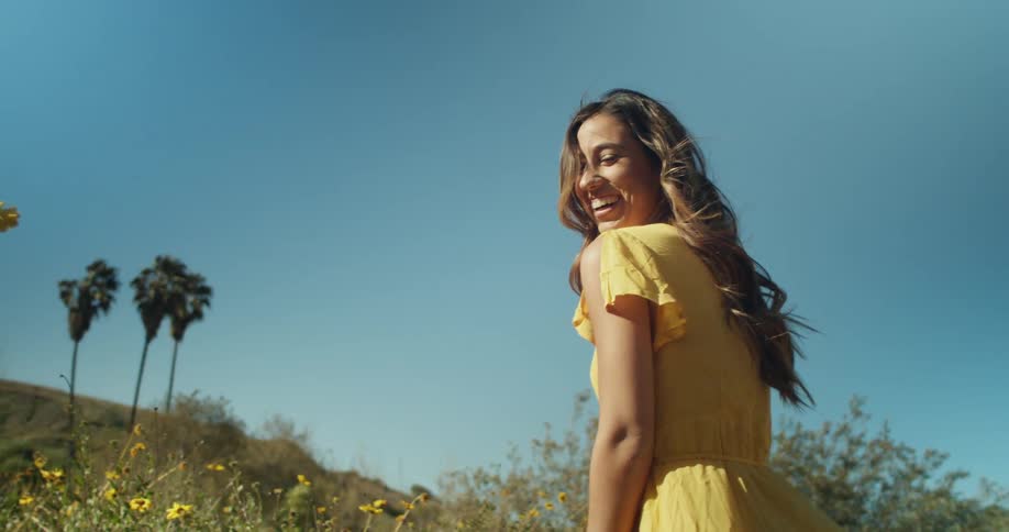 A woman stands in a field of flowers and laughs
