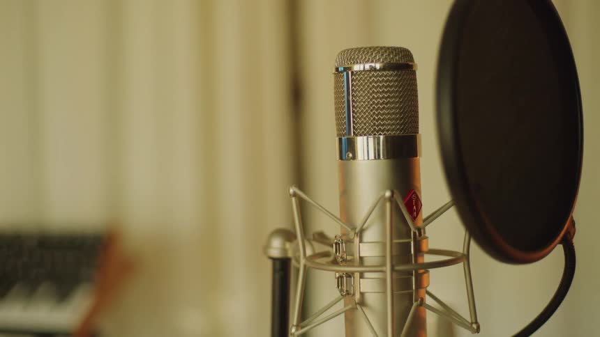 Microphone with a pop filter on a stand inside a studio