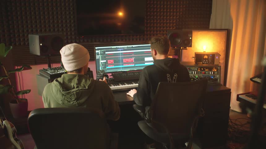 Two musicians editing music tracks inside a studio
