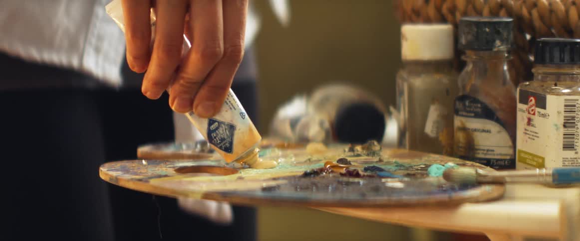 A person is mixing paint colors on a table