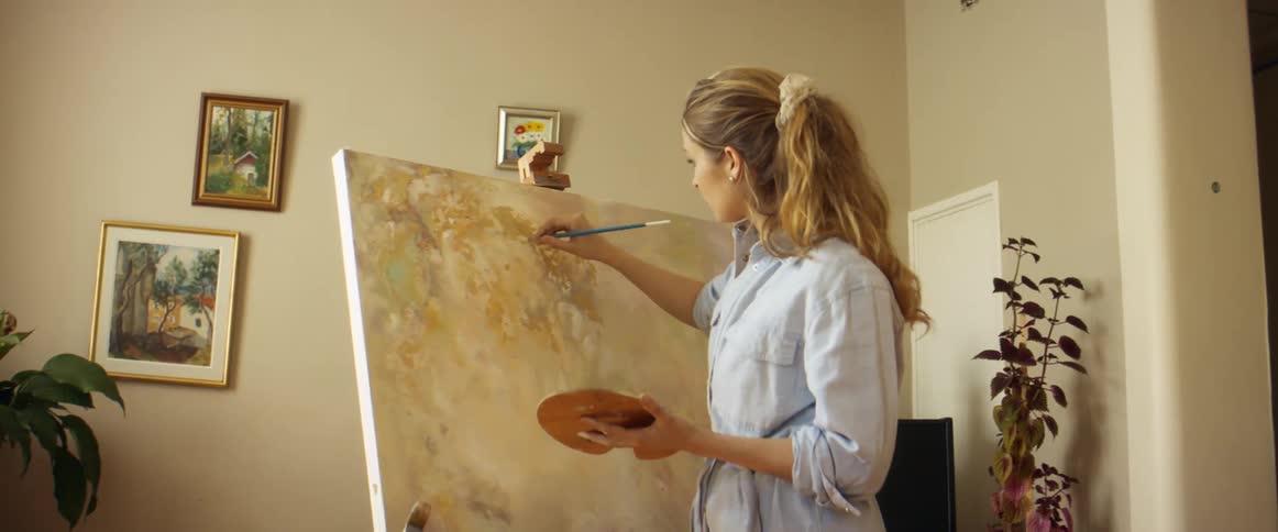 A woman is painting on a canvas