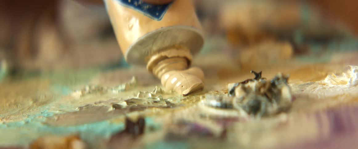 A person squeezes paint from a tube onto a palette