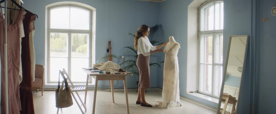 A seamstress pins a dress on a manequin