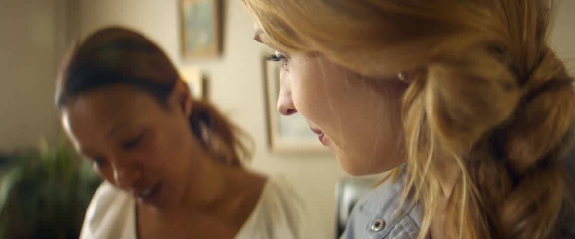 Two women stand in a room together and talk