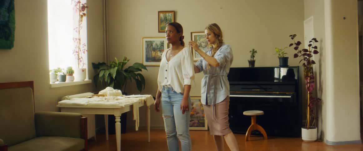 A woman is taking measurements of another woman using a measuring tape