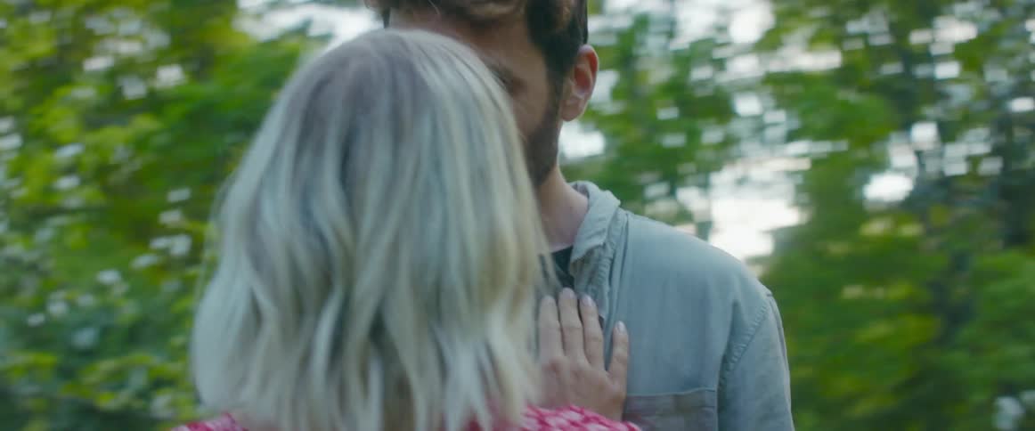 Two people together kissing in a park
