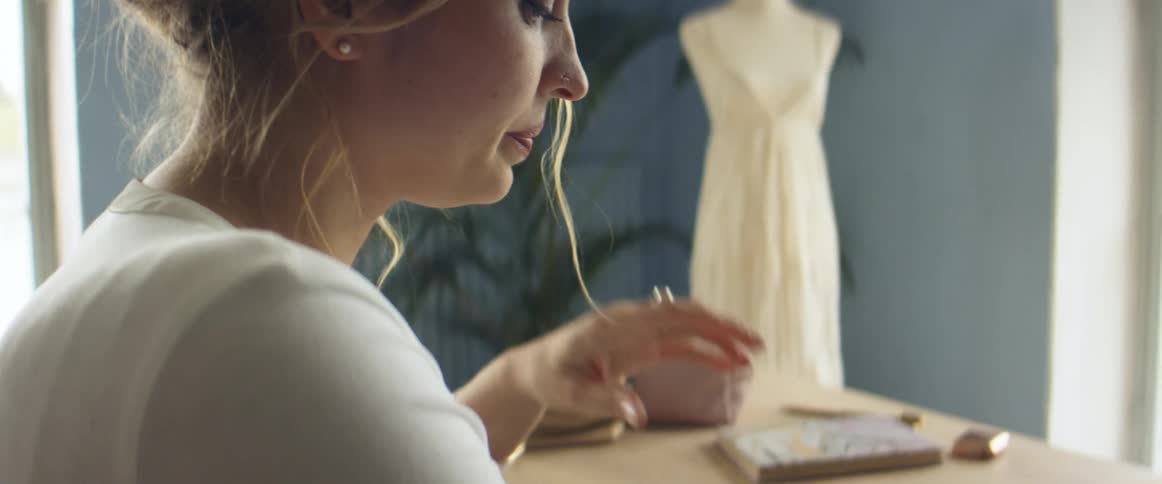 A woman sits at a table and sketches in a notepad