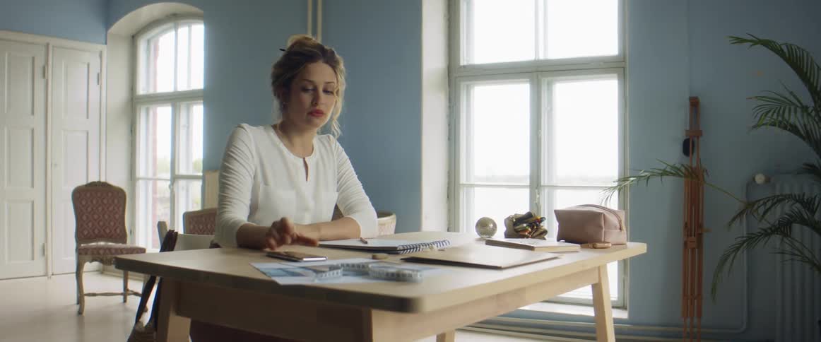 A woman sitting at a table puts her phone down and sighs looking sad