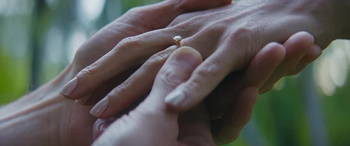 A man slips an engagement ring on to a womans finger