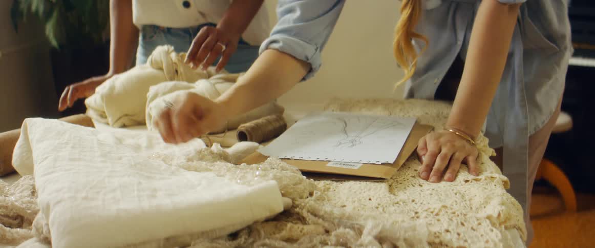 Two woman are discussing creation of a dress as they compare it to a sketch