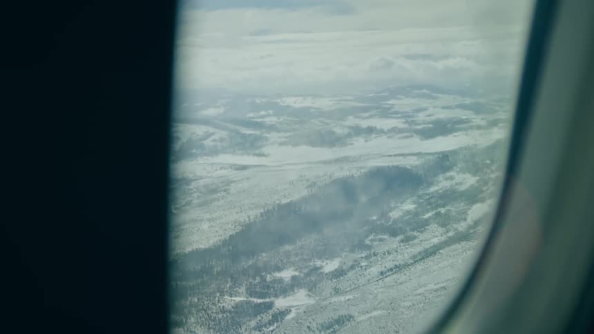 A shot taken from inside of a flying airplane window showing land from above