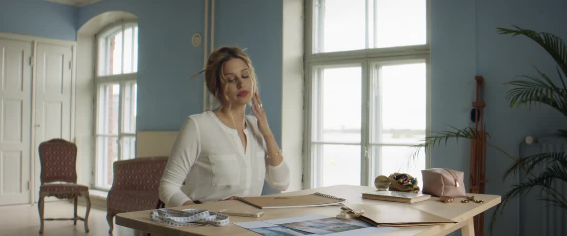 Clothes designer sits down in front of a desk inside her studio