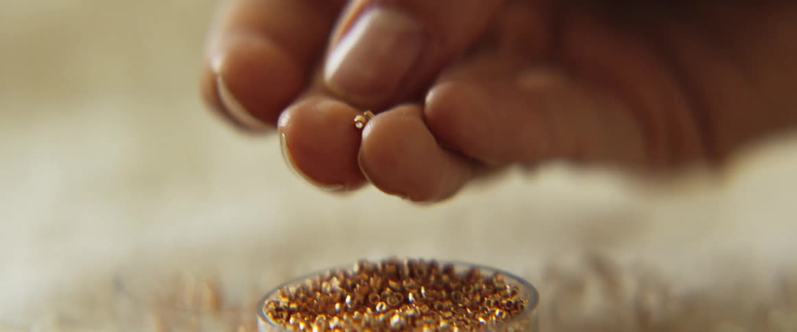A person picks beads up out of a container and runs them through their fingers