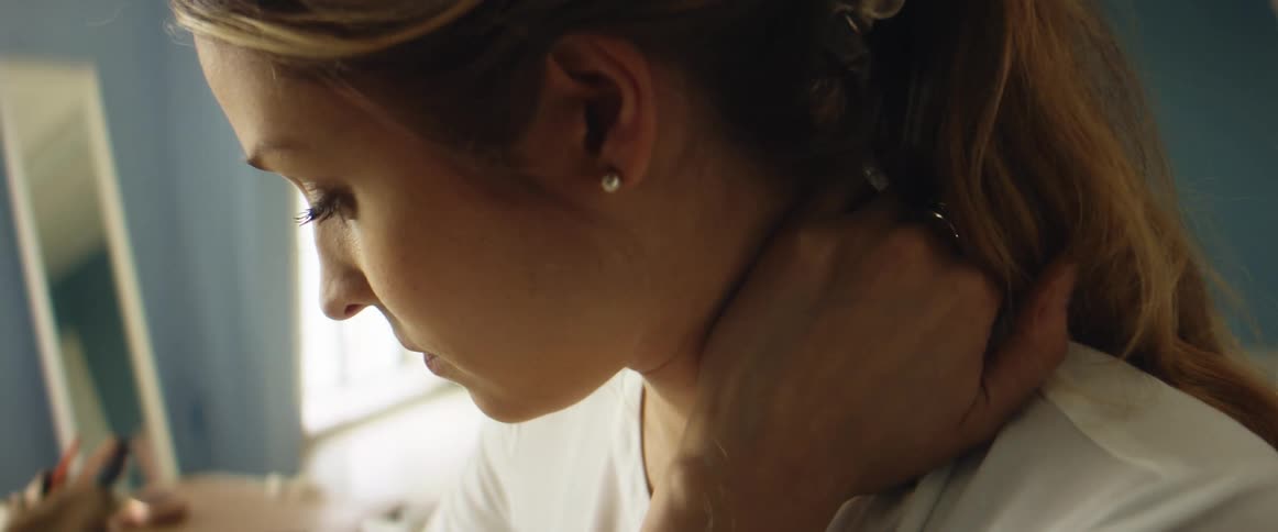 A woman massages her neck as she is working at a desk