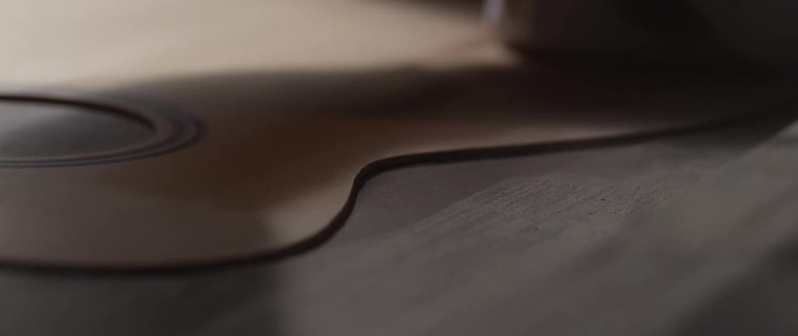 A person oils the wood of a guitar