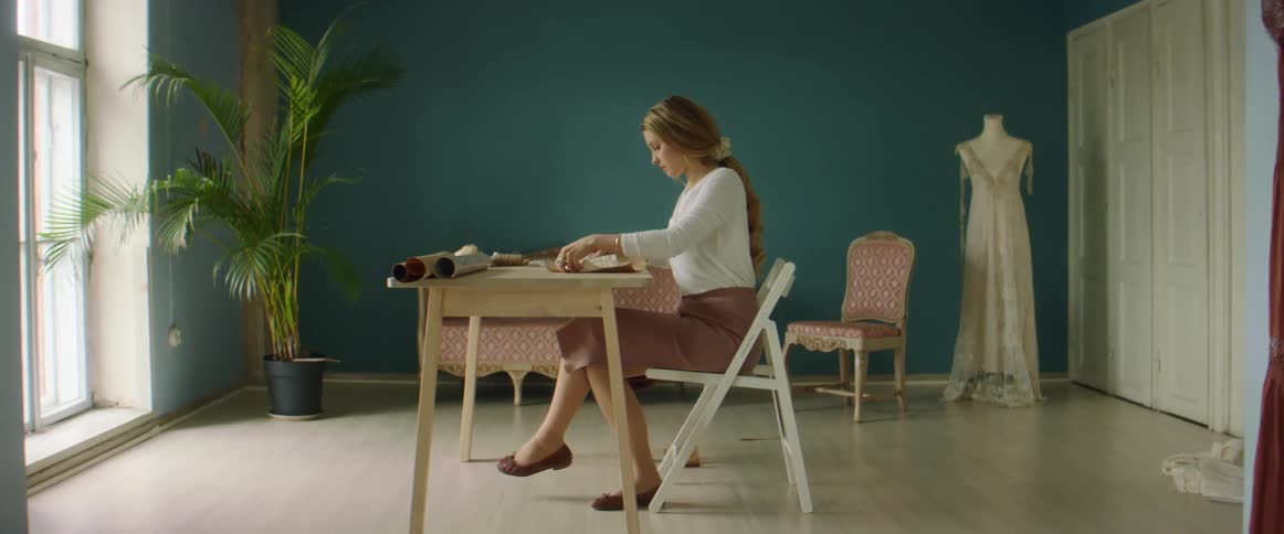A woman in a shop sits at an office and looks at swatches of material