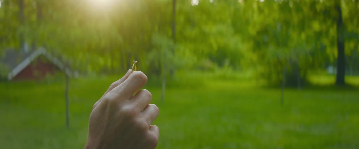 A man in a park holds a ring up in the air